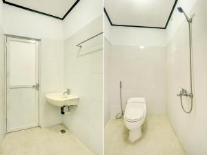 a white bathroom with a toilet and a sink at Bahtera Guest House in Denpasar