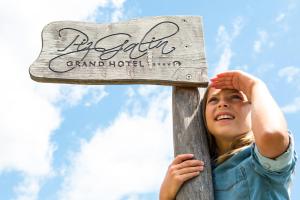 a young girl is holding onto a wooden cross at Piz Galin Grand Hotel Family & Wellness in Andalo