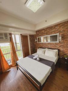a bedroom with a large bed and a brick wall at Pearljohn's Place Tagaytay Prime Residences in Tagaytay