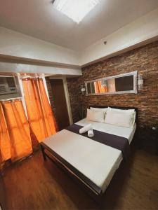 a bedroom with two beds and a brick wall at Pearljohn's Place Tagaytay Prime Residences in Tagaytay