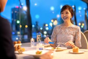een vrouw die aan een tafel zit eten bij Niigata Grand Hotel in Niigata