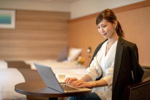 een vrouw die aan een tafel zit met behulp van een laptop computer bij Niigata Grand Hotel in Niigata