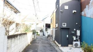 een smal steegje tussen twee gebouwen bij Kanamechō detached house in Tokyo