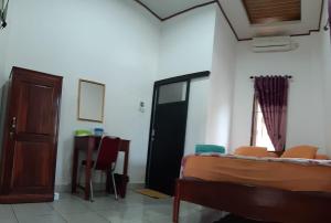 a bedroom with a bed and a door and a table at Losmen Ibu Hj. Tarjo in Palembang