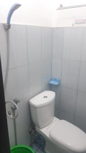 a white bathroom with a toilet and a shower at Losmen Ibu Hj. Tarjo in Palembang