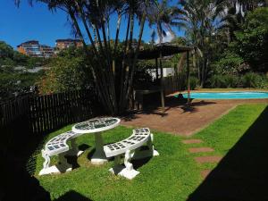 a table and two benches sitting in the grass at BillsBest Beach House in Margate