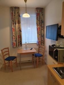 eine kleine Küche mit einem Tisch und Stühlen sowie einem Fenster in der Unterkunft Gästehaus Altstadttraum in Leer