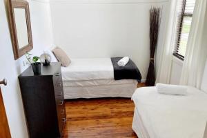 a bedroom with two beds and a dresser and a mirror at Fieldsend Cottage in East Maitland