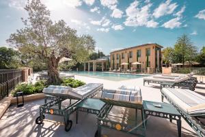 un patio con tavoli, sedie e piscina di Villa Saint-Ange ad Aix en Provence