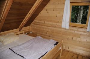 a bed in a log cabin with a window at Gorska hiška Vogar nad Bohinjskim jezerom in Bohinj