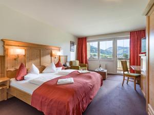 a bedroom with a large bed with a red blanket at Harmony Hotel Harfenwirt in Niederau