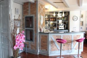un bar avec des tabourets roses devant un mur de briques dans l'établissement Auberge La Tomette, The Originals Relais, à Vitrac