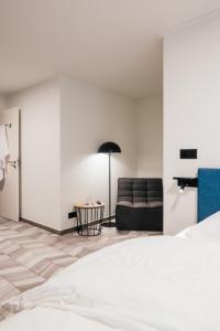 a bedroom with a bed, chair and a lamp at ROXI Residence Gent in Ghent