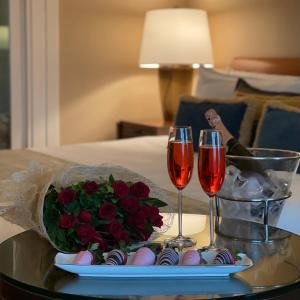a tray with two glasses of wine and a bouquet of red roses at The Leela Mumbai in Mumbai