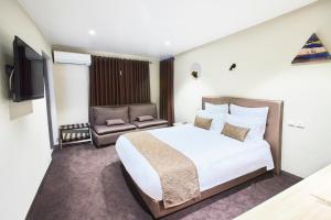 IvatoにあるFLY INN Madagascar HOTEL - Navette GRATUITE H24 - à 300m de l'Aéroport International Ivato-Antananarivoのベッドと椅子付きのホテルルーム