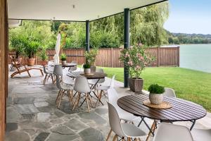 a patio with tables and chairs and a view of the water at Gasthaus Hotel Höhenwirt in Keutschach am See