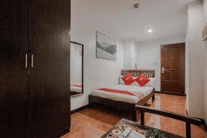 a bedroom with a bed with red pillows on it at Super OYO 714 Haeinsa Condotel in Manila