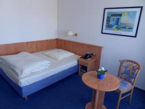 a bedroom with a bed and a table and a chair at Hotel Stadt Homburg - An den Universitätskliniken in Homburg