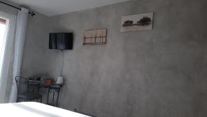 1 dormitorio con mesa y TV en la pared en LE CLOS CASTEL - Gîte équipé, en Casteljaloux