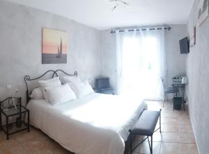 - une chambre avec un grand lit blanc et une fenêtre dans l'établissement LE CLOS CASTEL - Gîte équipé, à Casteljaloux