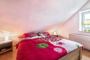 um quarto com uma cama com um edredão vermelho em Ferienhaus Ongi em Friedrichskoog-Spitz