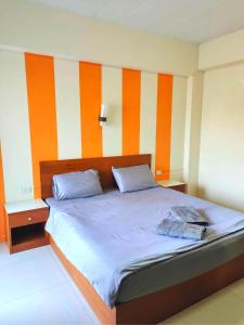 a bedroom with a large bed with orange and white stripes at โรงแรมวิจิตรพร อุบล VJP Hotel Ubon in Ubon Ratchathani