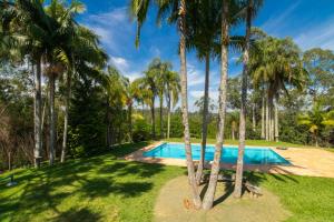 an image of a swimming pool surrounded by palm trees at Chácara com churrasqueira e piscina em Cotia in Diadema