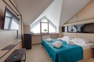 a bedroom with a bed with blue sheets and windows at Hotel Riders Equides club in Lesniki