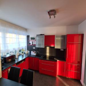 uma cozinha com armários vermelhos e bancadas pretas em Dům Mnichov Bazén Klimatizace em Vrbno pod Pradědem