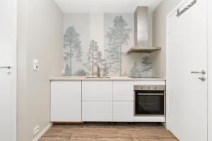 a kitchen with white cabinets and trees on the wall at Central Studio Apartment Apt 103 in Stavanger