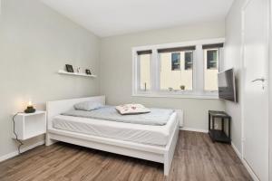 a white bedroom with a bed and a window at Central Studio Apartment Apt 103 in Stavanger