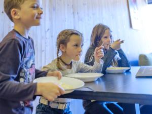 un grupo de niños sentados en una mesa comiendo comida en Almenland Apartment Passail en Passail