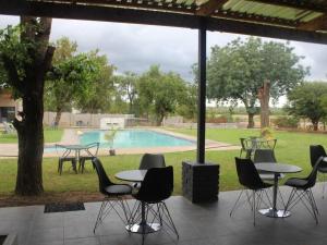 un patio con mesas y sillas y una piscina en Dam Vista Retreat, en Giyani
