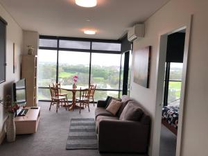 - un salon avec un canapé et une table avec des chaises dans l'établissement Parkview Modern Apartment w Parking @ Olympic Park, à Sydney