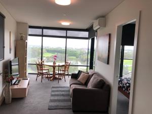 Una sala de estar con un sofá y una mesa con sillas. en Parkview Modern Apartment w Parking @ Olympic Park, en Sídney