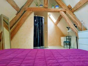 1 dormitorio con cama morada en el ático en La Maison entièrement équipée - Boulangerie, en Saint-Pierre-les-Étieux