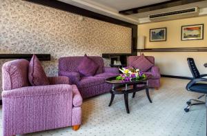 a living room with purple chairs and a table at Petra Guest House Hotel in Wadi Musa