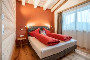 een slaapkamer met oranje muren en een bed met rode kussens bij Naturhaus am Arlberg in Warth am Arlberg