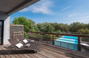 a deck with a table and chairs next to a pool at VILLA TORRACCIA 4 Étoiles in Sainte-Lucie de Porto-Vecchio