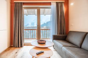 a living room with a couch and a large window at Naturhaus am Arlberg in Warth am Arlberg