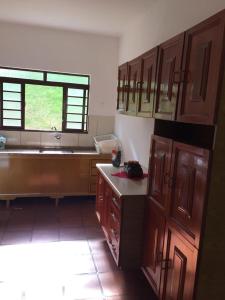 een keuken met houten kasten, een wastafel en een raam bij chácara legal in Socorro +4 foto's