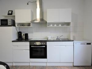 una cocina con armarios blancos y horno negro en Monteurhaus Scheidter 40, en Saarbrücken