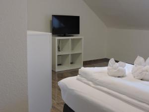Pokój z 2 łóżkami z białymi poduszkami i telewizorem w obiekcie Ferienwohnungen Haus Scheidter 40 w mieście Saarbrücken