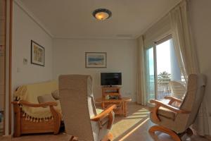 een woonkamer met stoelen, een bank en een televisie bij 020 - Senya Gran Playa 001 - comfortHOLIDAYS in Santa Pola