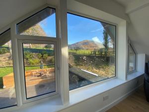 a room with two windows with a view of a wooden deck at Latrigg View in Keswick