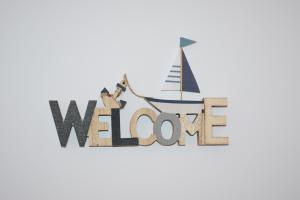 a wooden sign with a sailboat and the words welcome at VILASUITES Beach, Sand & Menta in Villajoyosa