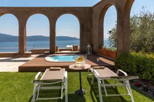 a patio with a table and chairs and a pool at Le Selve Lake View Villas in Toscolano Maderno