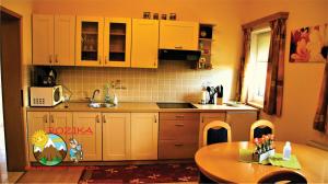 cocina con armarios blancos, mesa y fregadero en Apartment Rozika, en Slovenj Gradec