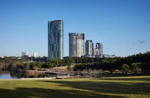 a view of a city with tall buildings and a park at Parkview Modern Apartment w Parking @ Olympic Park in Sydney
