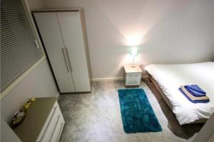 a small bedroom with a bed and a blue rug at StayZo Modern Studio Apartment 1 in Bradford City in Bradford